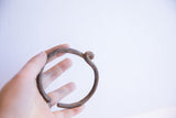 The rustic, handmade form of a vintage African knotted cuff bracelet held in hand.