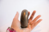 The substantial form and etched surface of an antique African cuff held in hand.