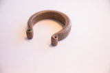 Angled view of the heavy, antique African cuff bracelet highlighting its open form.
