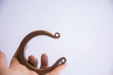 Profile of a heavy antique African cuff showing its substantial form and curled terminals.