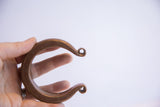 Antique African heavy cuff bracelet held to show its substantial scale and curved form.