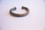 The overall shape of a twisted African cuff bracelet with a time-softened oxidized finish.