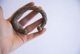 Antique African twist cuff bracelet with oxidized patina held in hand to show scale.