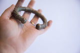 Antique twist cuff with a dark oxidized finish held in hand to demonstrate its scale.