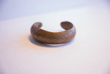 The curved form and time-softened patina of a handmade African cuff bracelet.