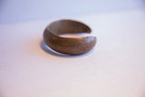 The open C-shape and weathered, dark patina of an antique African cuff bracelet.