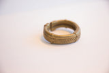 The circular form and textured craftsmanship of a vintage African bronze cuff bracelet.
