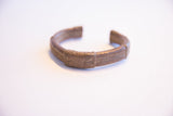 Angled view of a vintage African copper cuff, showing its handcrafted texture and aged patina.