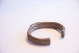 Angled view of the vintage copper alloy cuff's curve and aged, rustic surface.