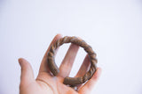 Antique African twist cuff bracelet held in hand to demonstrate its scale and form.