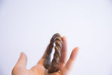 Antique twist cuff bracelet held to display its substantial, handcrafted form and patina.