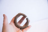 In-hand view of an antique African bronze cuff, showing its substantial form and textured patina.