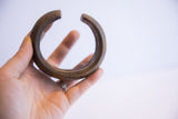 Antique African cuff bracelet held to show its substantial shape and textured patina.
