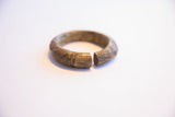 Carved details and time-softened patina at the opening of a bronze cuff bracelet.