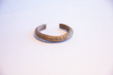 The open design and profile of a vintage African bronze currency bracelet.