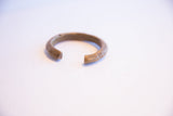 The open ends of the vintage bronze cuff showing etched details and a matte patina.