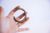Vintage African bronze cuff with etched patterns held in hand to show its small size.
