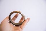 Vintage African bronze cuff bracelet held in a hand showing its scale and etched ends.