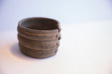 Angled view of the vintage African cuff showing its banded design and dark, aged patina.