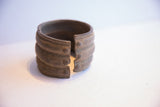 Aged metal patina and studded detail at the opening of the wide African cuff.
