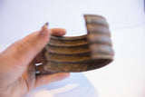 A hand holds the vintage African cuff, highlighting its wide ribbed profile.