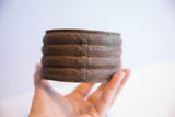 The solid, oxidized form of the vintage African cuff bracelet held in hand.
