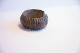 The ribbed, oxidized surface and curved opening of the African cuff.
