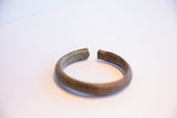 The textured, oxidized surface and open ends of the vintage African cuff bracelet.