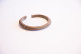 Profile view of the vintage African bracelet's open cuff and ridged surface.