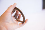 A hand holding the vintage African cuff bracelet, showing its scale and ridged texture.