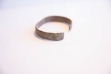 Detailed view of the vintage cuff bracelet's end, showing its handmade texture and aged surface.