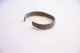The open profile of a handmade African cuff with an aged metal patina.
