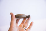 The substantial thickness and rustic, aged patina on the edge of a vintage African bracelet.