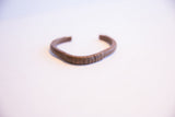 Hand-etched lines along the curved center of the vintage copper cuff.