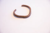 Side profile of a vintage African copper cuff showing its handmade form and aged patina.