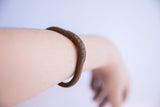 Vintage copper cuff bracelet with an aged patina worn on the arm.