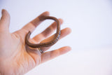 Vintage copper cuff bracelet with a warm, textured patina held in hand.