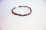 Vintage African cuff bracelet showing its twisted, hand-forged texture and dark patina.