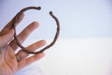 Vintage African twisted metal cuff bracelet held in hand for scale.