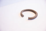 Vintage African cuff bracelet showing its C-shape, ribbed texture, and open ends.