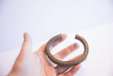 Vintage African currency bracelet held in hand, showing its scale and ridged texture.