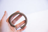 Hand holding a collectible vintage African cuff with a grooved, patinated finish.