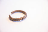 Angled profile of a vintage African cuff bracelet showing its deep patina and hand-carved segments.
