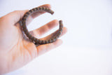 Vintage African cuff bracelet with a ridged texture, held in hand for scale.