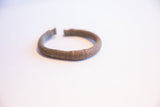Profile view of a vintage African currency bracelet showing its oxidized patina.