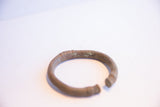 The open C-shape of a vintage African cuff with an oxidized, textured finish.