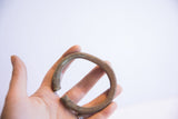 A hand holds the vintage oxidized African cuff, showing its texture and scale.