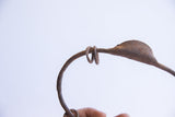 Close view of the coiled metal detail and rattle showing an age-worn, oxidized patina.