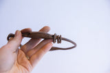 A hand holds the vintage Yoruba dance bracelet showing its rustic, hand-forged details.
