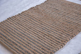 Textured weave of a handmade undyed jute rug with muted gray-blue bands.